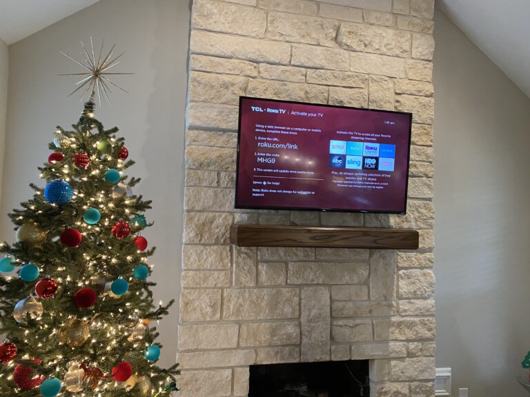 tv mounting over fireplace next to a Christmas tree - american installs